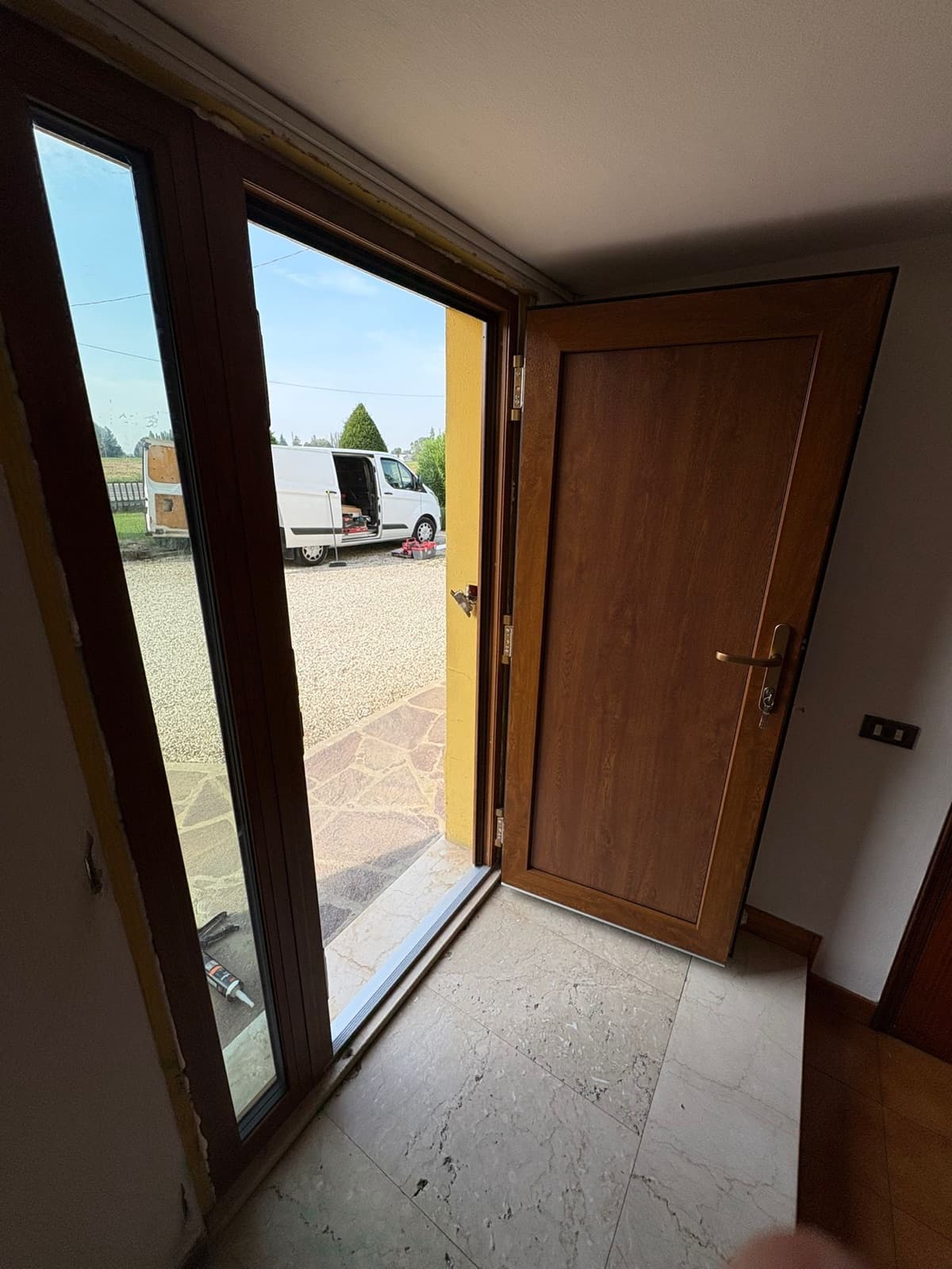 Porta d'ingresso in PVC effetto legno con vetrata laterale, vista da interno