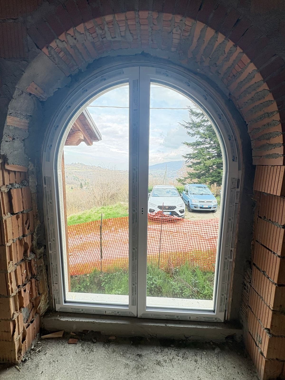 Finestra ad arco in PVC bianco con muratura in mattoni a vista